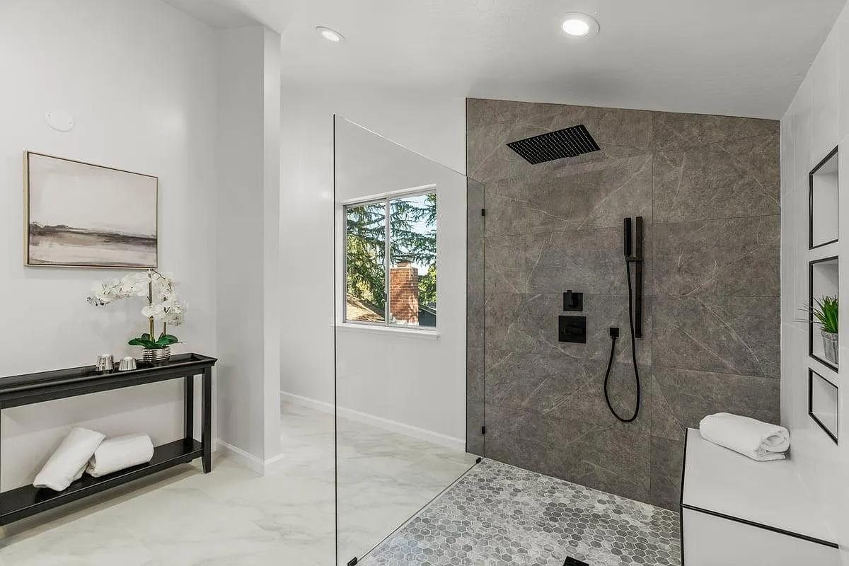 Renovated bathroom with a walk-in tile shower and glass panel